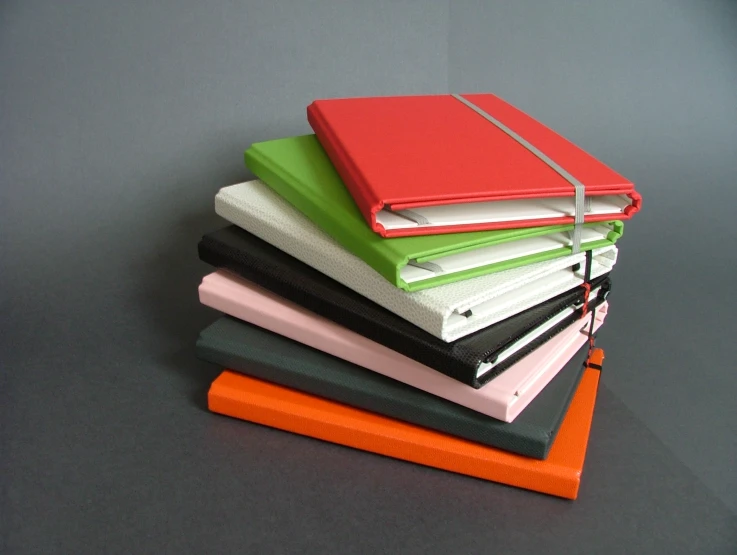a stack of notebooks in different colors on a table