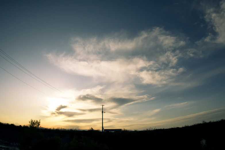the silhouette of a telephone pole against a dark blue sky