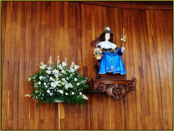 a wooden wall with a small flower arrangement next to it and an ornament that is decorated on it