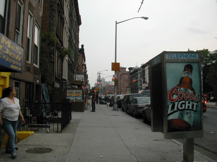 a street sign for a beer company and a woman walking by