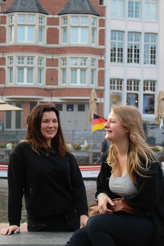 two pretty women sitting next to each other on a bench