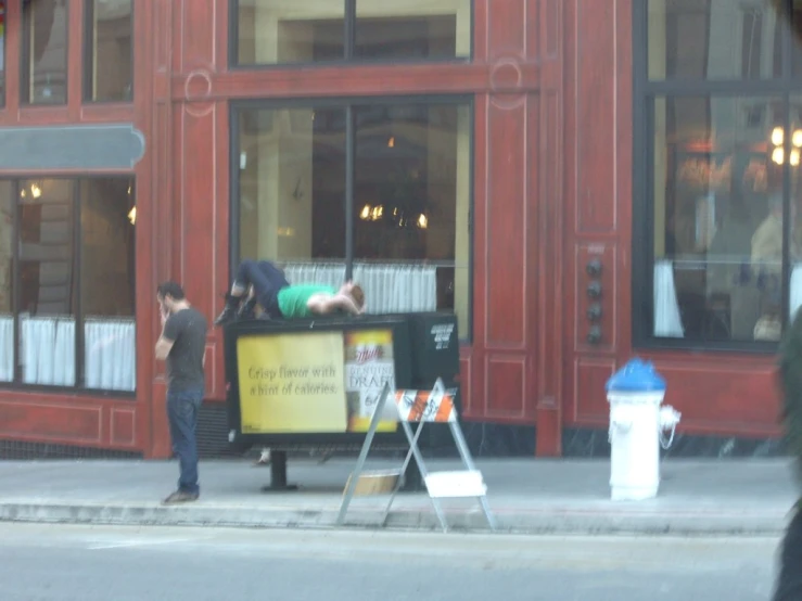 a person putting trash into a large container in front of a store