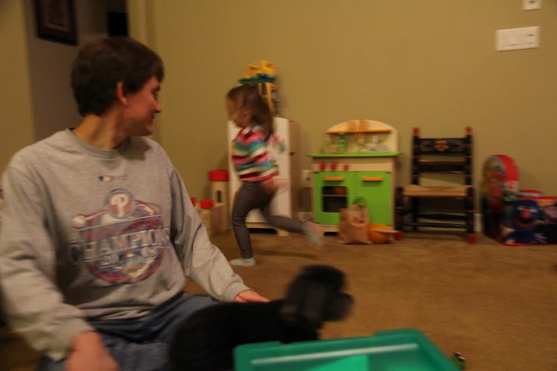 two people playing games with a black dog in a living room