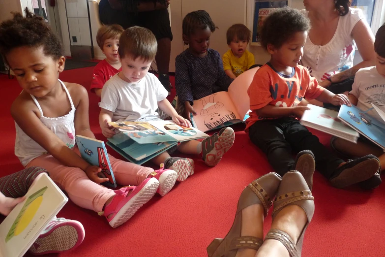 a group of children sitting on the ground with books