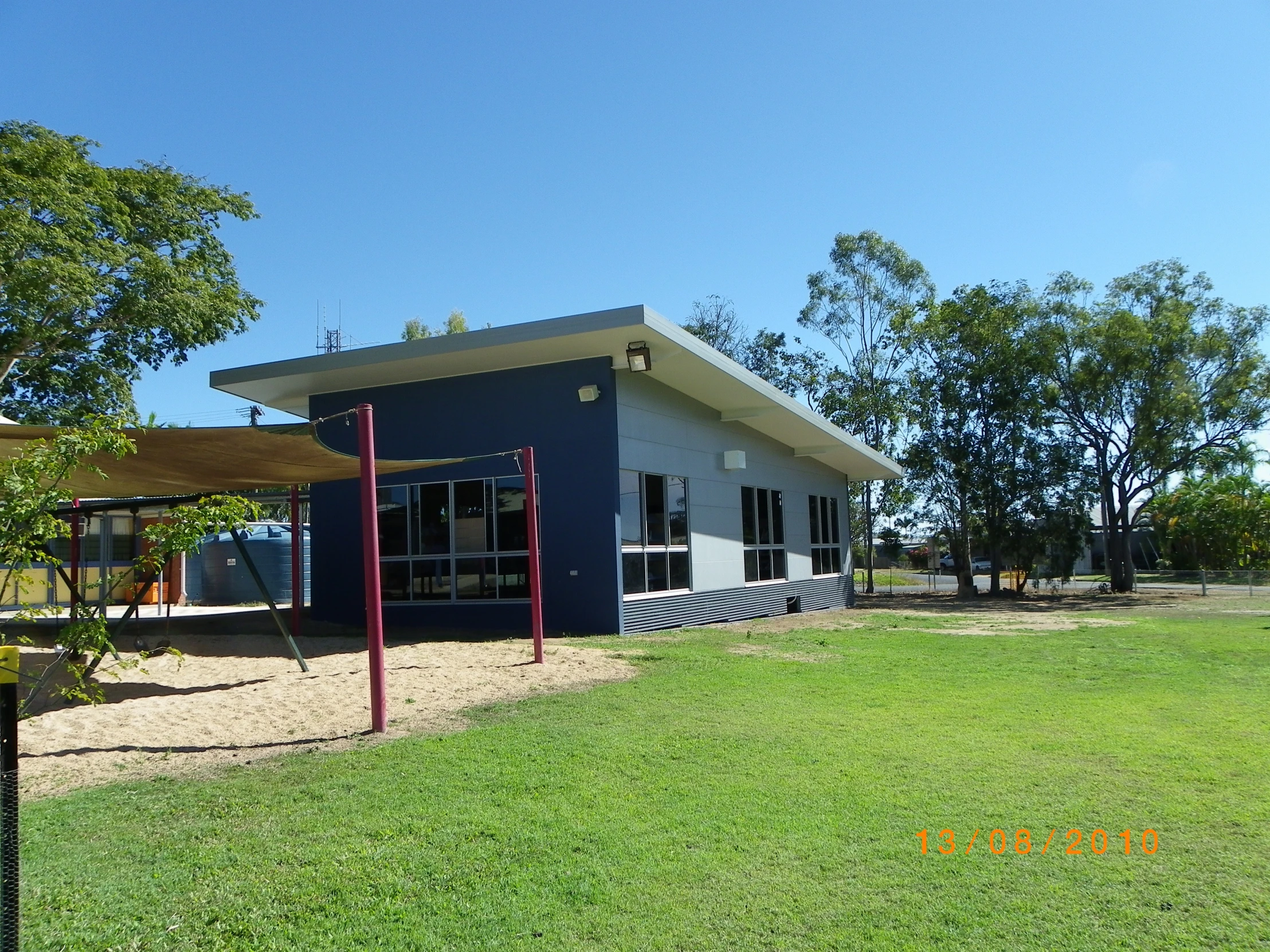 a little blue building in a large grassy field