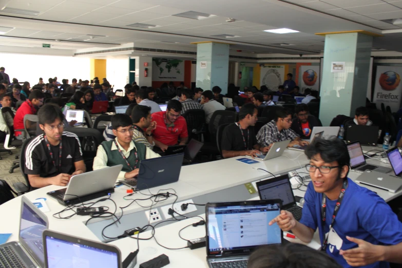 a group of people work together in a room filled with laptop computers