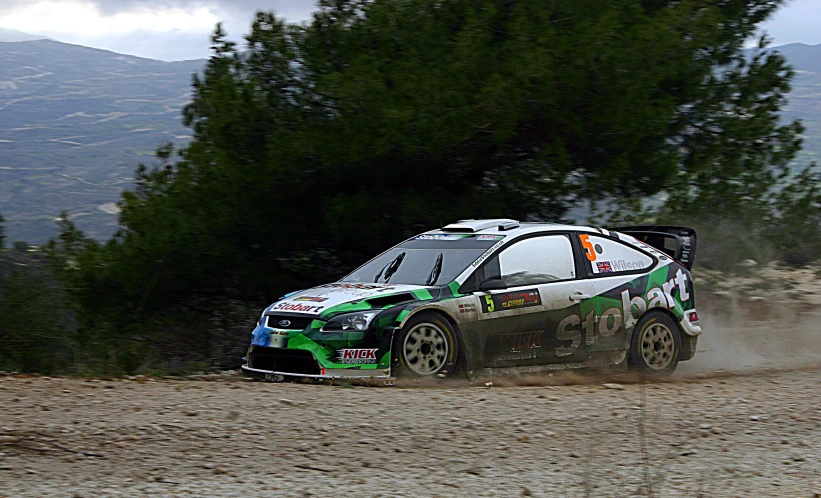 two men in racing cars going down a dirt track