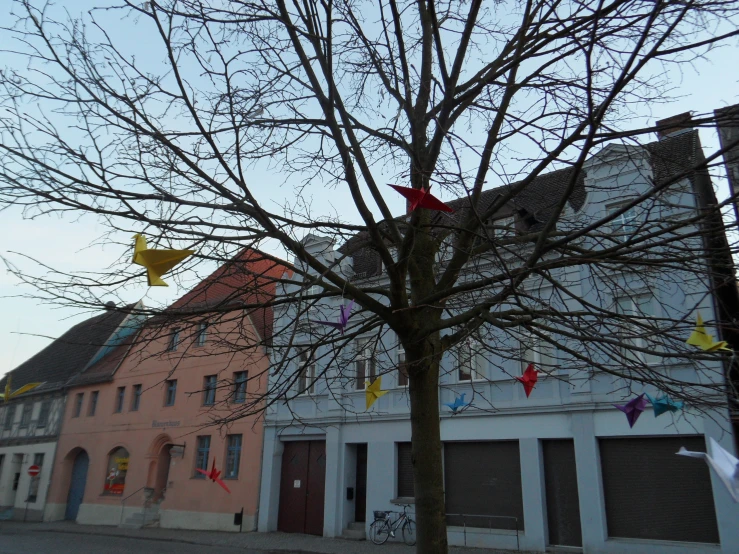 two buildings on the street are decorated with kites