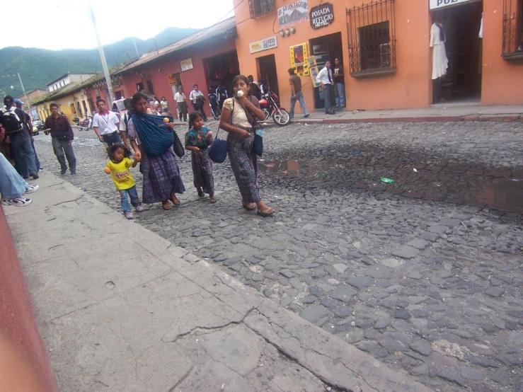 people gather outside of a city street that has a cobblestone sidewalk
