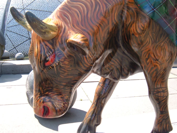 a wooden statue of a bull with a tartan scarf around its neck