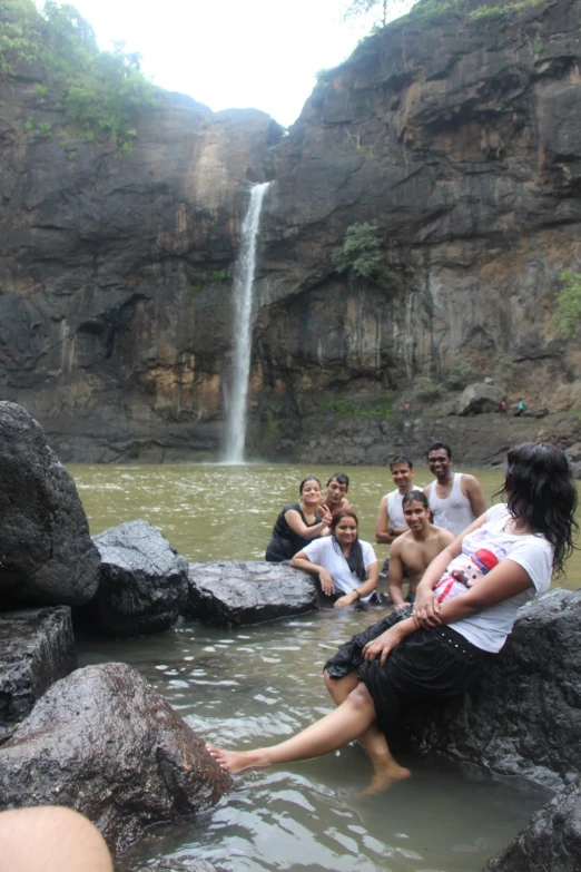 people sitting around rocks next to a waterfall