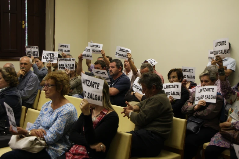 people sitting in chairs holding up signs in a conference room