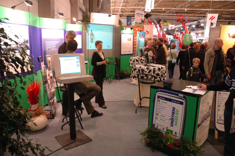 a crowd of people at an exhibit looking at computers