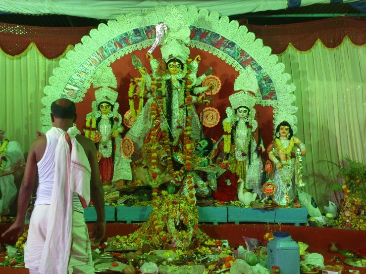 a man stands next to the statue of lord rama