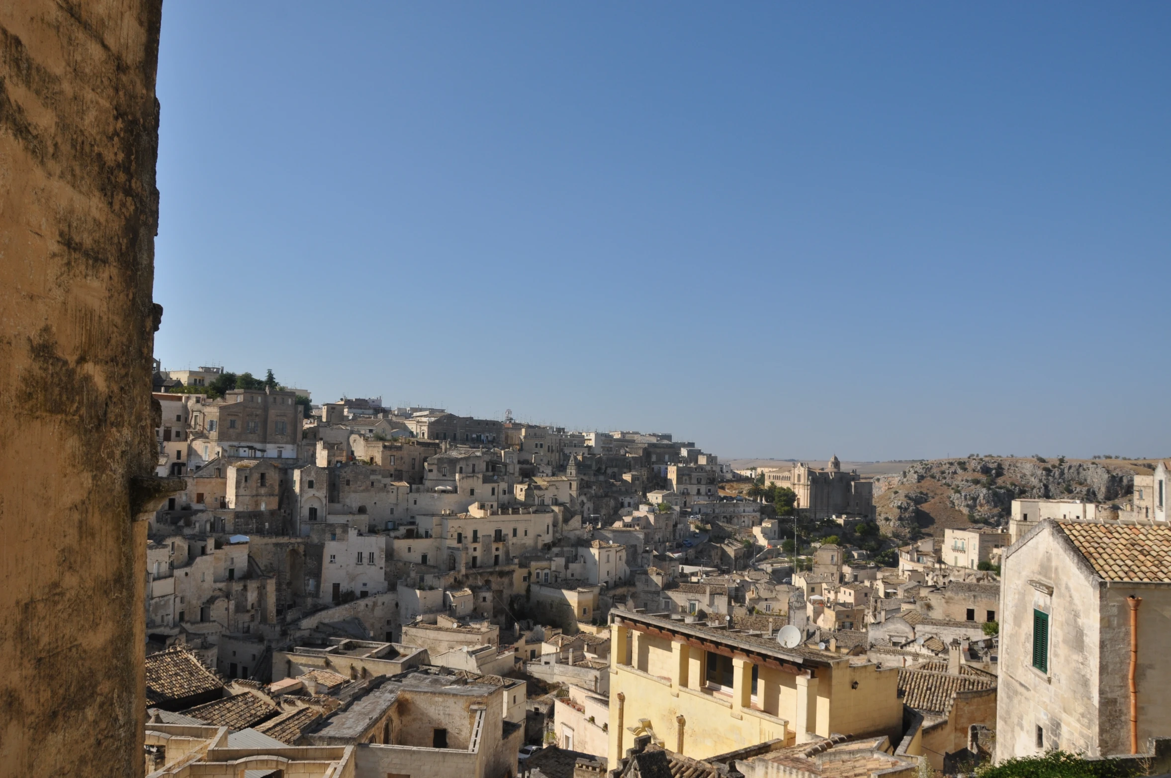 old city buildings, some with yellow walls, are seen from the hillside