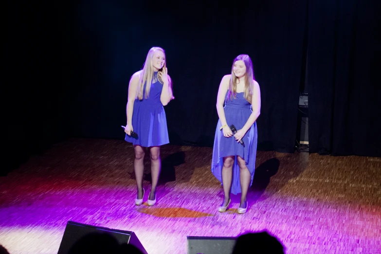 two s on stage wearing purple dresses