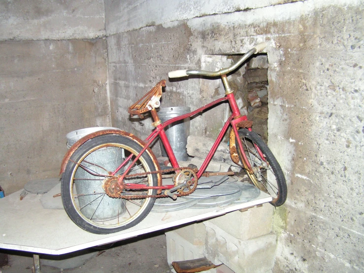 an old red bicycle in an unfinished room