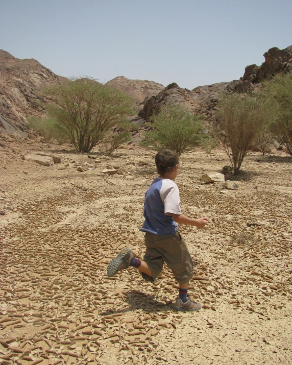 a young man in the desert throwing a frisbee