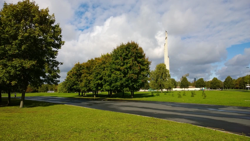 a large green park that has a few trees and a bench