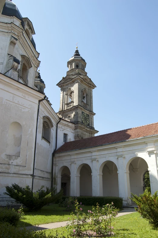 the clock tower of an old, white building with arches on one side