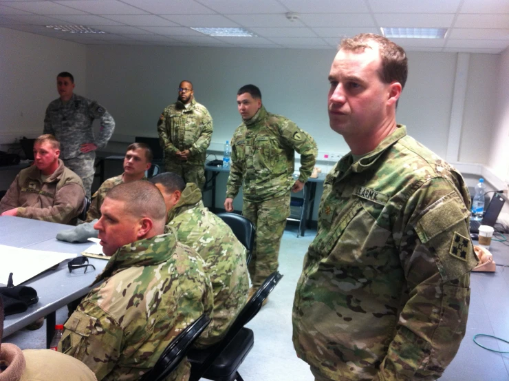 several men in fatigues stand and look at the camera