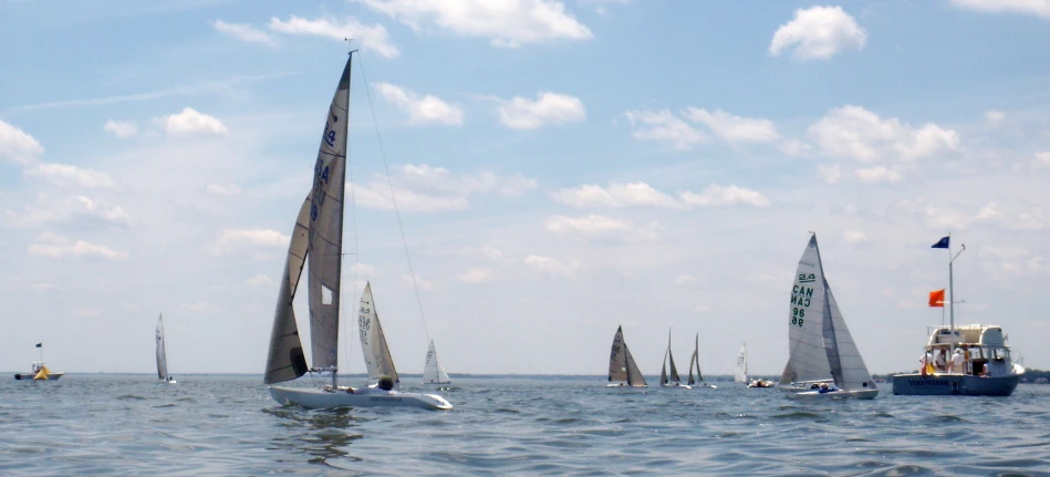 a group of small sail boats with flags sailing in the ocean