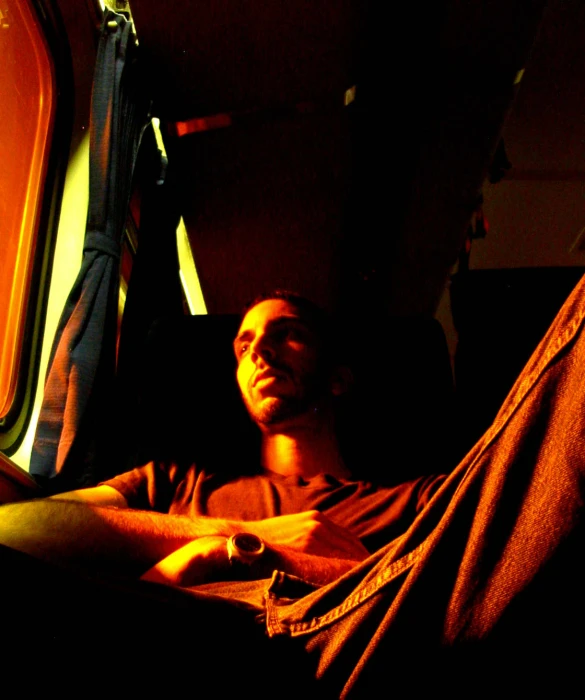a man sitting in the dark looking out of a window