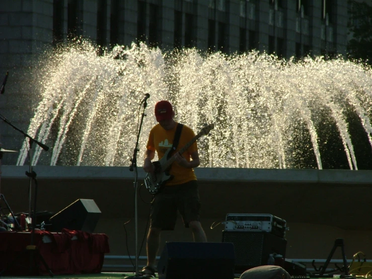 a man is playing music in front of the fountain