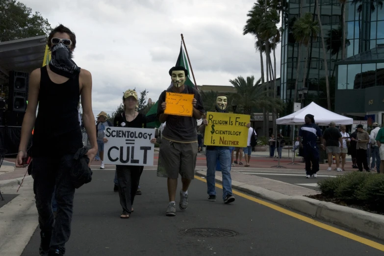 a group of people walk down the street holding signs