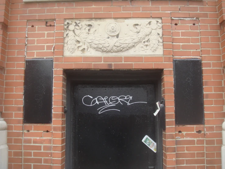 a brick wall with black paint on the side and the words calero painted on it