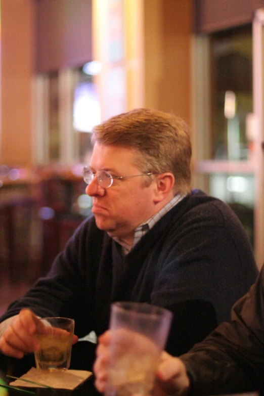 two men sitting at a table with drinks