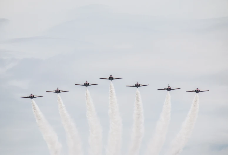 six planes with white smoke trailing their tails