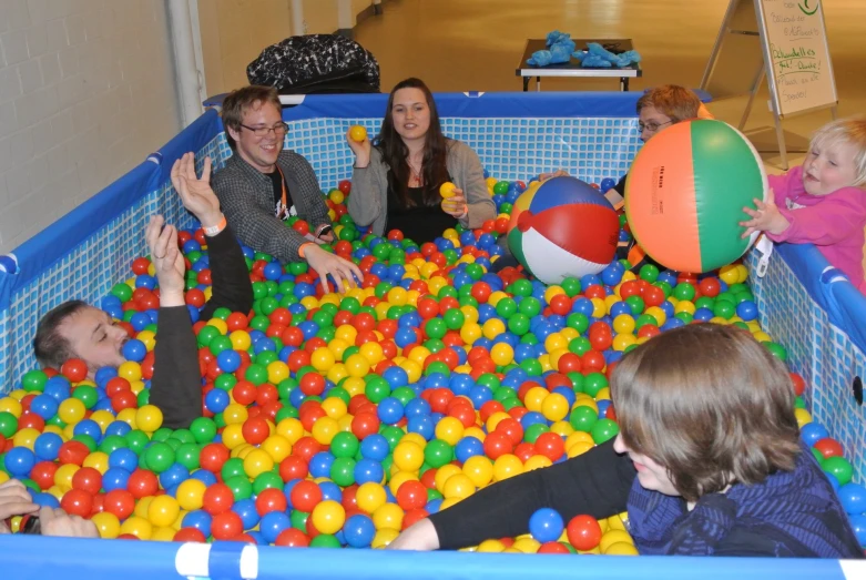 people are sitting in the pool with balls and one is clapping