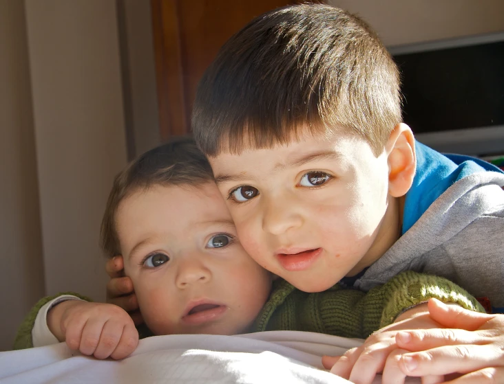 two children lying in bed under a white blanket