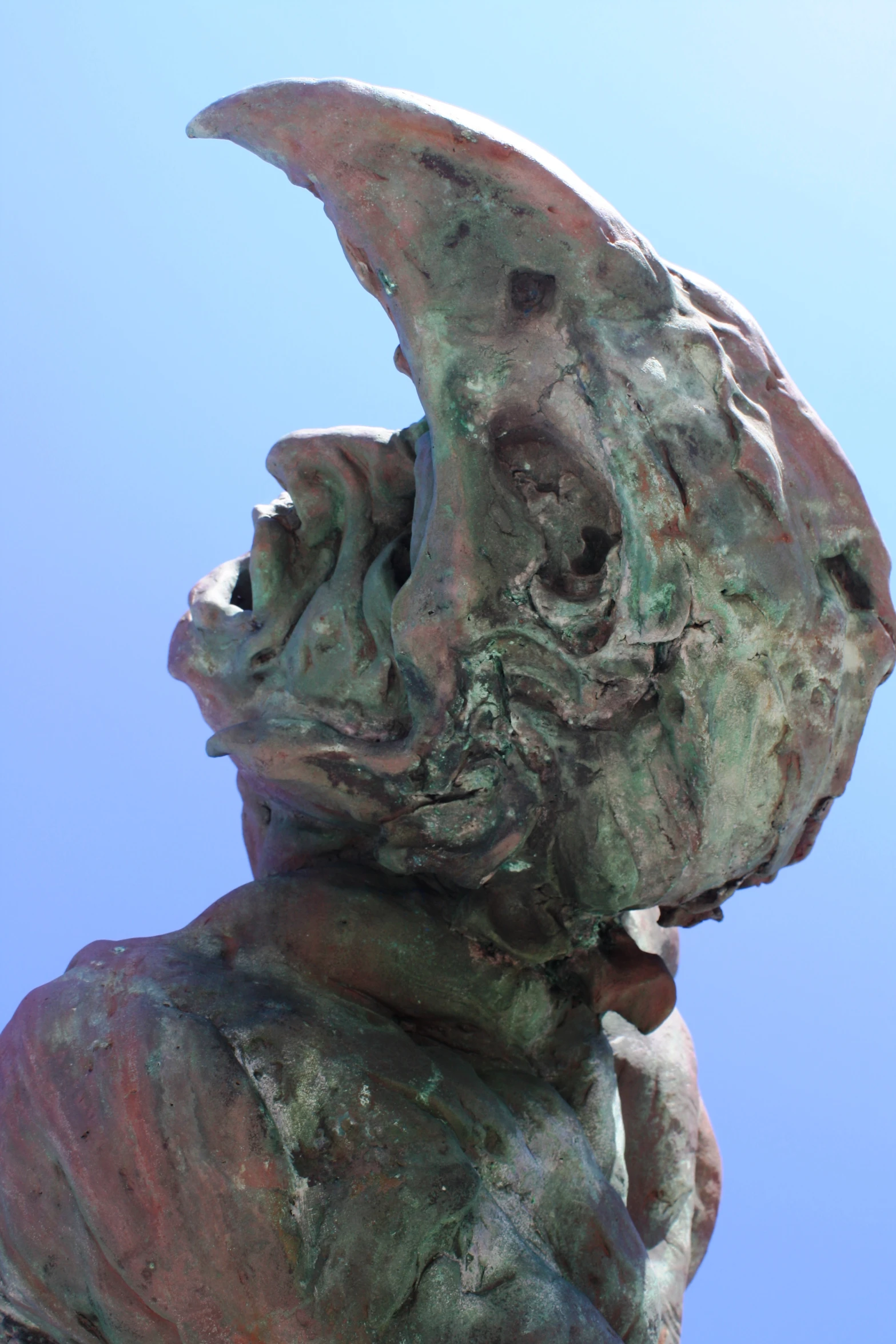 the side view of an artistic statue with a blue sky behind it