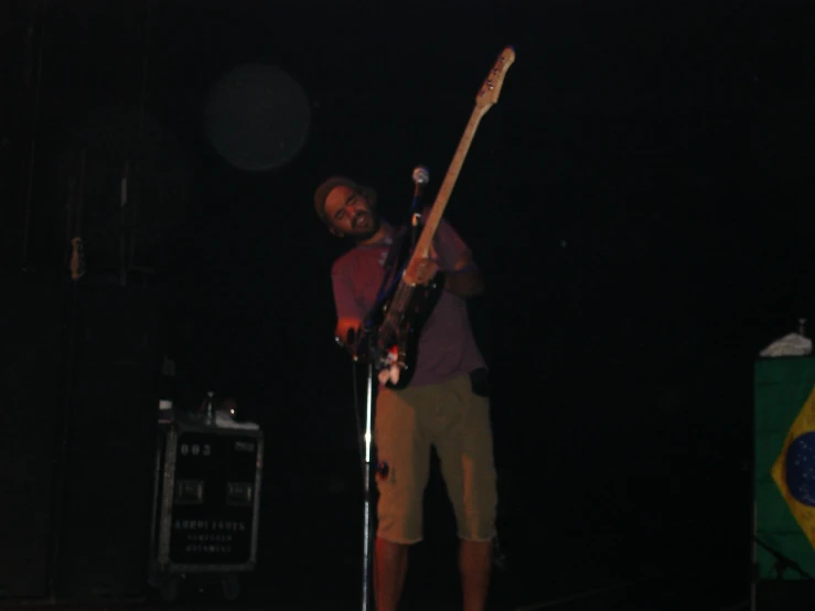 the man with a guitar standing in front of microphone