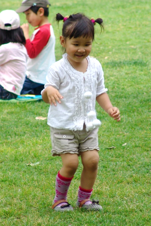 a little girl in tights and a shirt standing on the grass