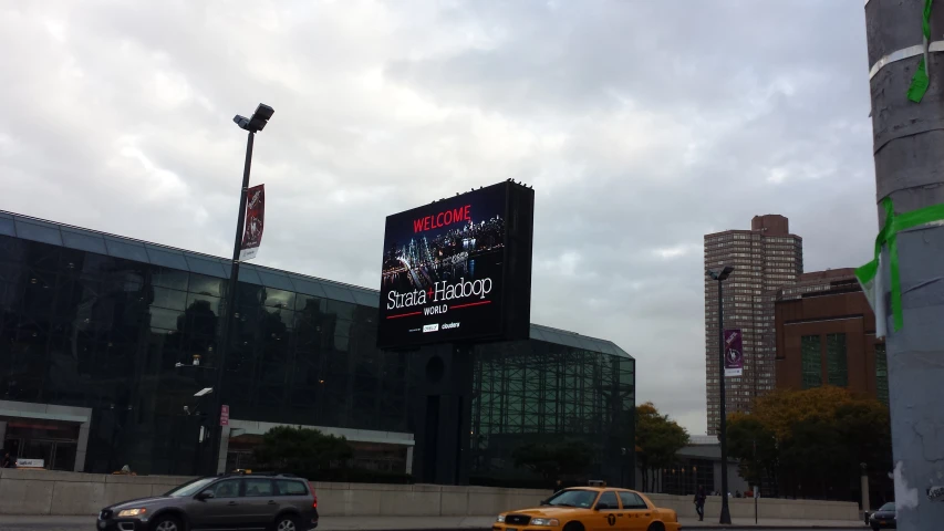 a billboard sits near some cars on a city street