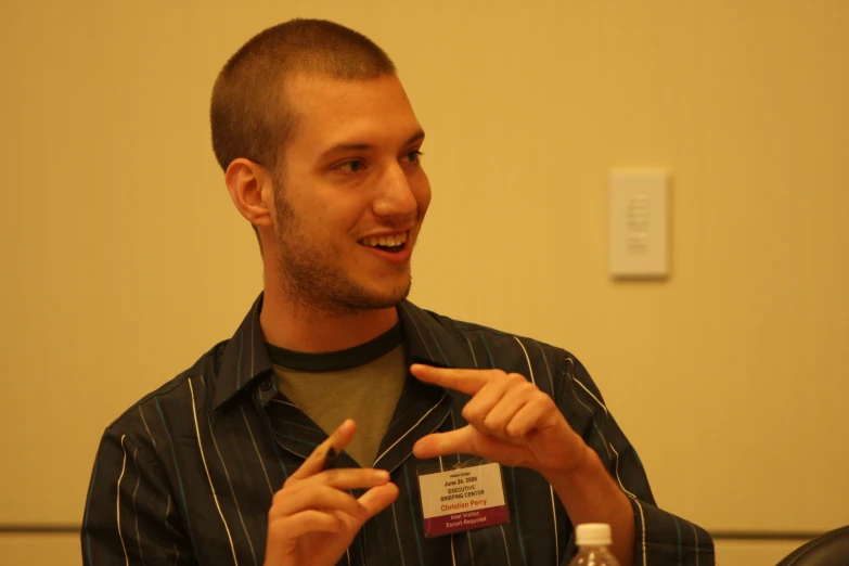 a man points at an identification badge on his shirt