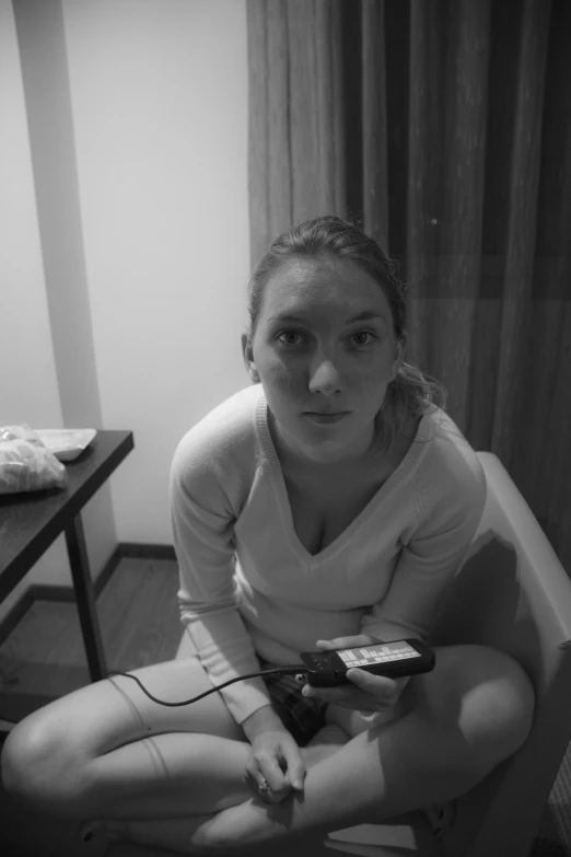 a woman in underwear sits on the floor and holds a video game remote