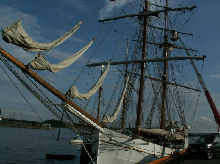 the sailboat is moored near a parked car