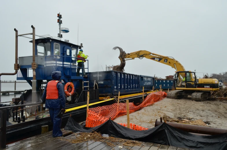 construction workers stand by a large blue ship