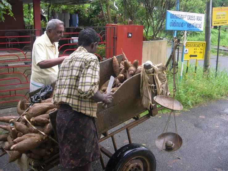 two men hing a cart filled with potatoes