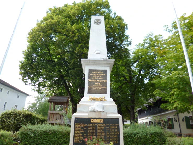 the war memorial is in a garden surrounded by trees