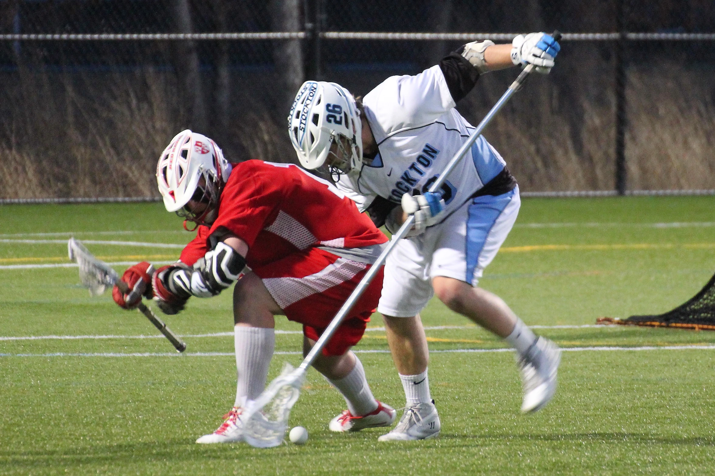 a couple of people on a field playing a game of lacrosse