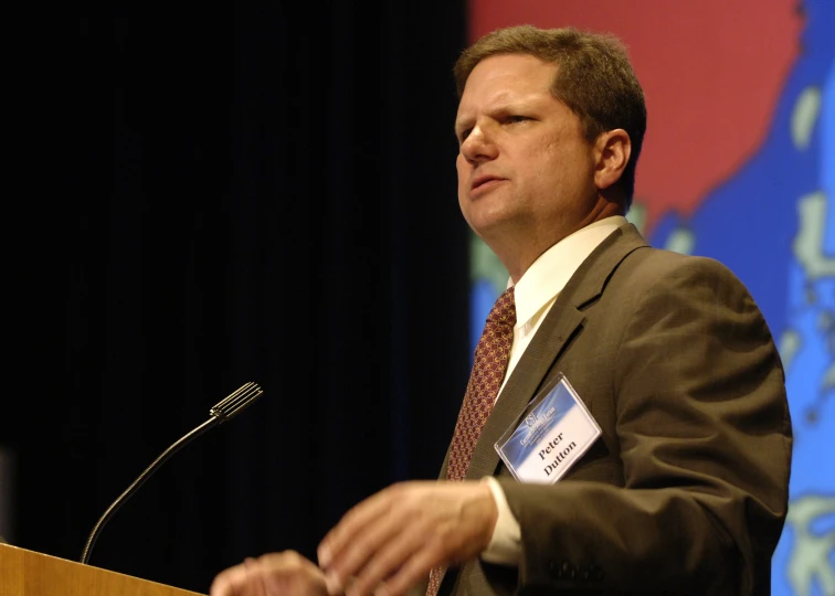 a man stands at the podium and speaks into the microphone