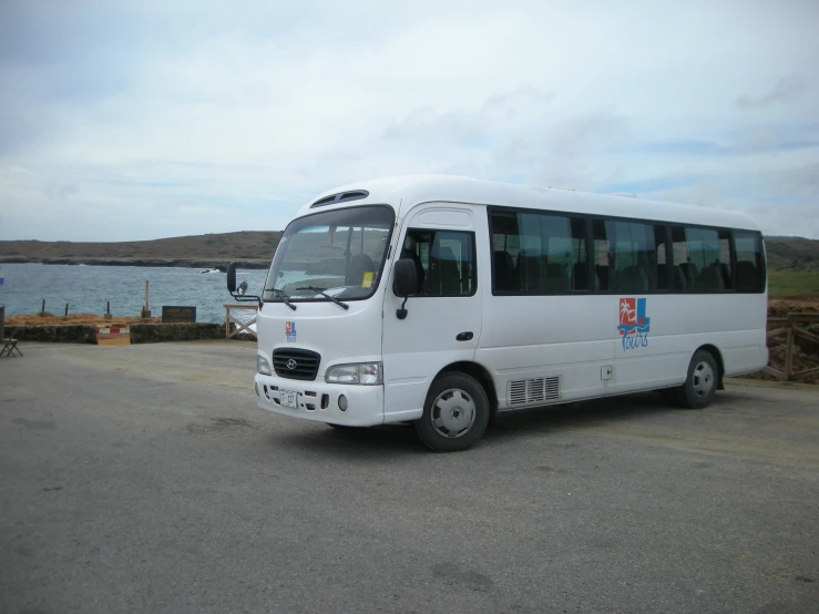 a white bus parked on the side of the road by the ocean