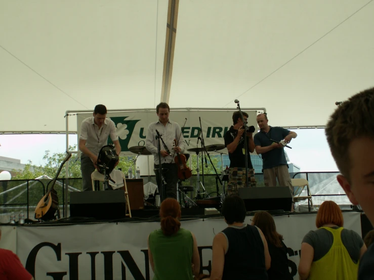 band playing on stage in open air tent during daytime