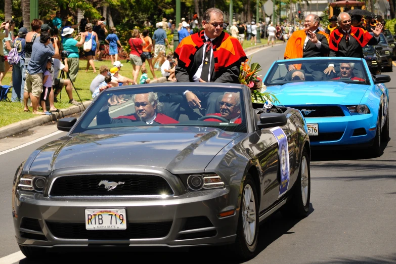 people standing outside a car driving down the street in front of a crowd