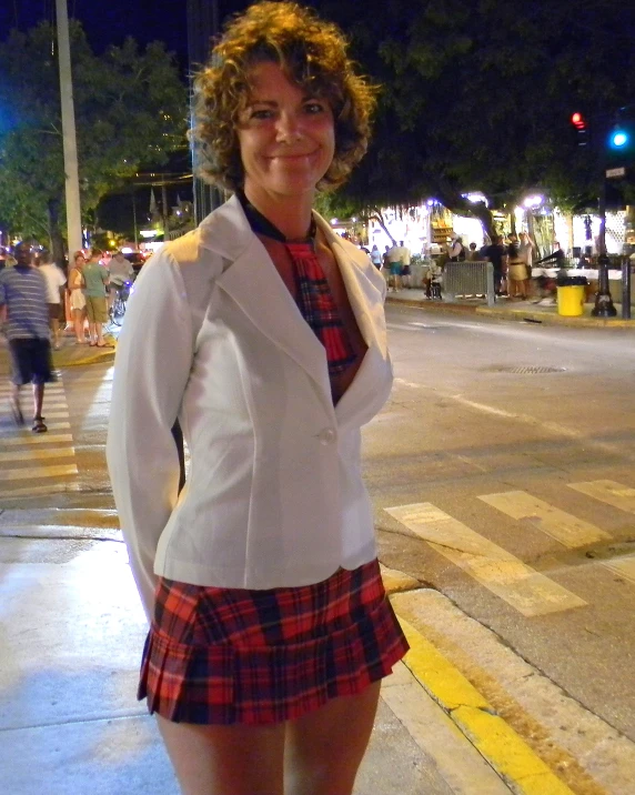 a woman wearing a red and white plaid skirt is standing on a sidewalk